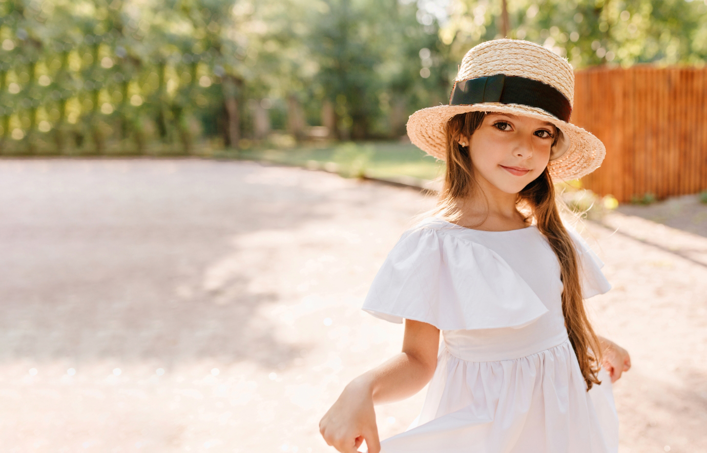 pretty-girl-big-straw-hat-playing-with-her-white-dress-while-posing-park-with-wooden-fence-portrait-lovely-female-kid-wears-boater-decorated-with-ribbon-dancing-road.jpg